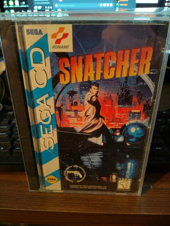A copy of Snatcher on Sega CD in the original case in front of a computer.