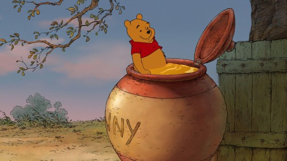 Whinnie the Pooh sitting in a giant jar of honey.